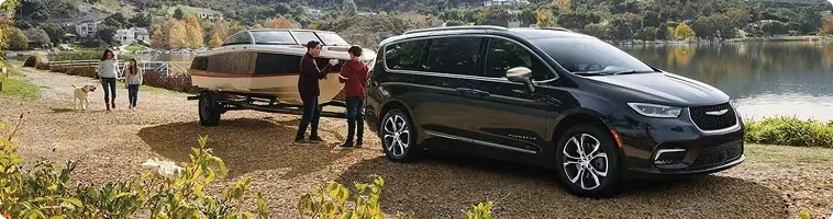 2026 Chrysler Pacifica towing a small trailer compared with the 2026 Toyota Sienna