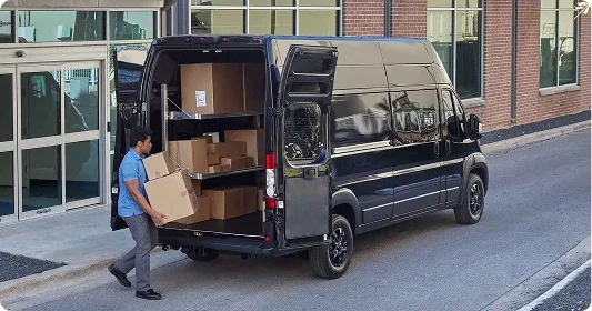 Worker loading cardboard boxes into the rear of a Ram ProMaster cargo van