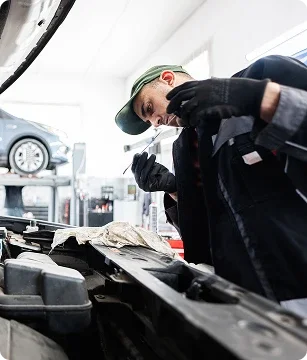 Service technician working under the hood of a vehicle in a shop bay